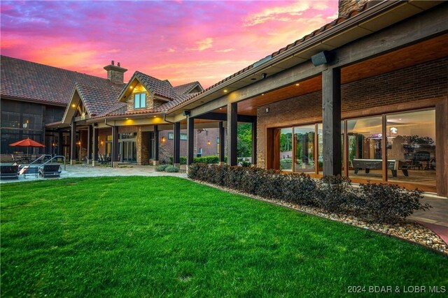 back house at dusk with a lawn