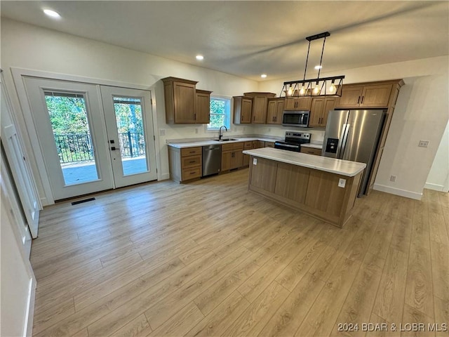 kitchen featuring stainless steel appliances, a kitchen island, light countertops, brown cabinets, and pendant lighting