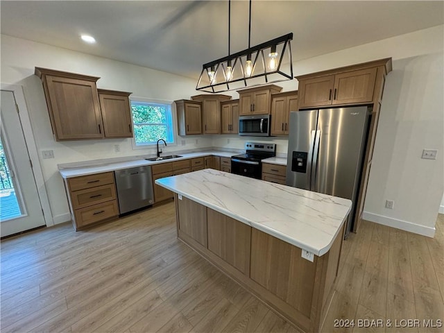 kitchen with brown cabinetry, a kitchen island, decorative light fixtures, stainless steel appliances, and a sink