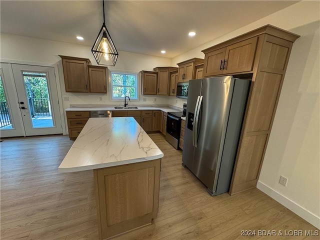 kitchen featuring a center island, brown cabinets, hanging light fixtures, appliances with stainless steel finishes, and a sink