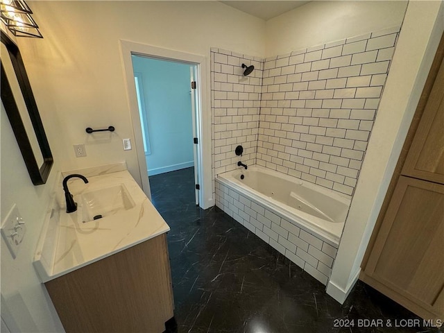 bathroom with marble finish floor, baseboards, tiled shower / bath, and vanity