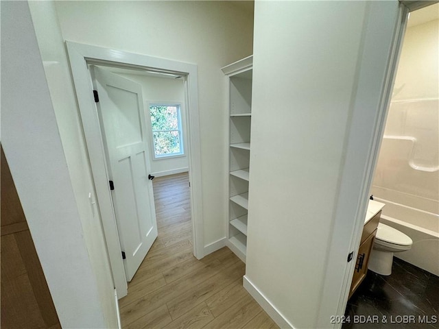 walk in closet with light wood finished floors