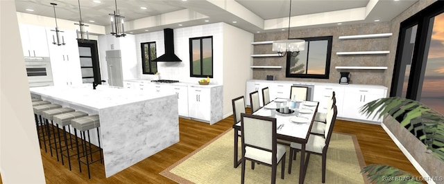 kitchen featuring ventilation hood, a center island, wood-type flooring, and white cabinetry