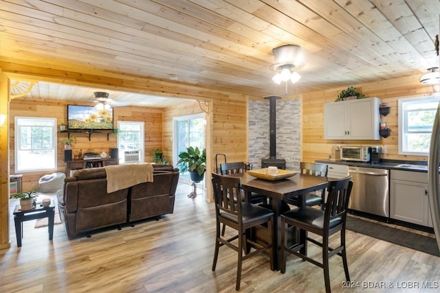 dining room with light hardwood / wood-style floors, wood walls, and a wealth of natural light