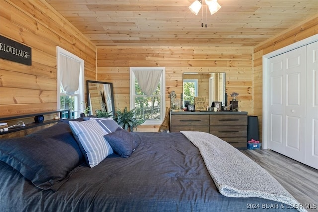 bedroom featuring a closet, wooden ceiling, wooden walls, and hardwood / wood-style floors