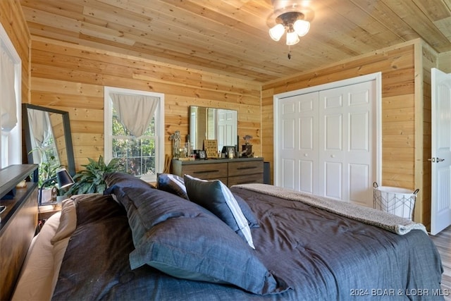 bedroom featuring a closet, hardwood / wood-style flooring, wooden ceiling, and wood walls