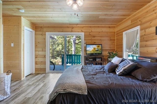 bedroom with access to exterior, wooden walls, wooden ceiling, and light wood-type flooring