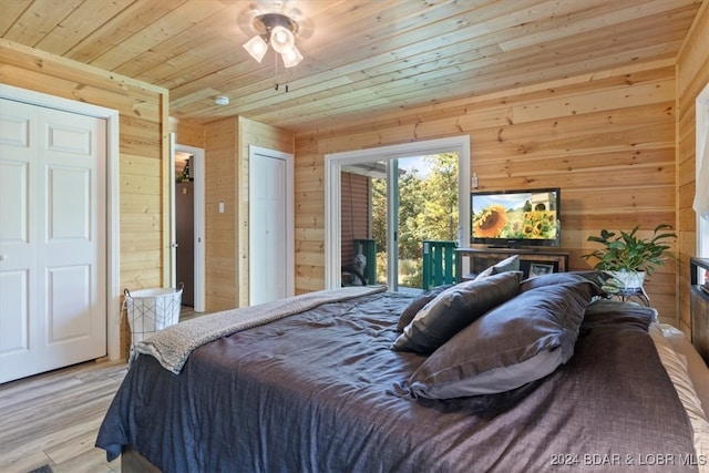 bedroom featuring light hardwood / wood-style flooring, ceiling fan, access to outside, and wood walls