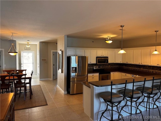 kitchen with a kitchen breakfast bar, light tile patterned floors, white cabinetry, and appliances with stainless steel finishes