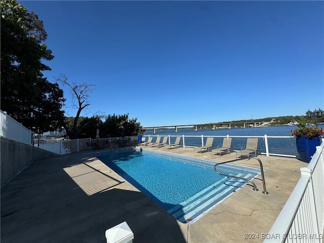 view of pool featuring a water view and a patio