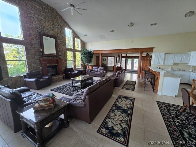 tiled living room featuring ceiling fan, french doors, high vaulted ceiling, and a brick fireplace