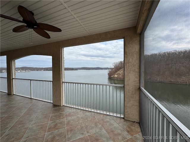 unfurnished sunroom with ceiling fan and a water view