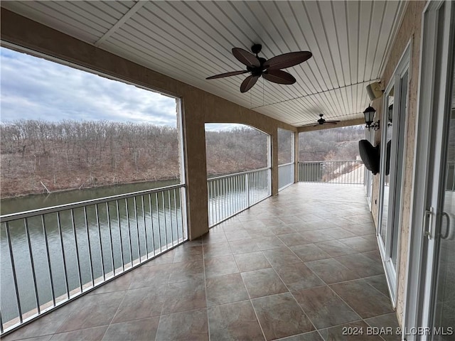 unfurnished sunroom with ceiling fan and a water view