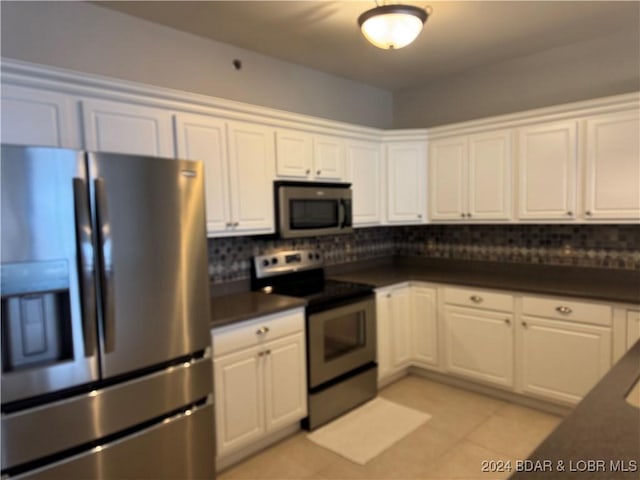 kitchen with white cabinets, appliances with stainless steel finishes, backsplash, and light tile patterned flooring