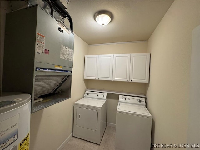 clothes washing area with separate washer and dryer, water heater, light tile patterned flooring, and cabinets