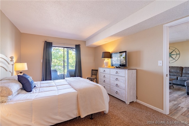 bedroom featuring a textured ceiling, hardwood / wood-style floors, and access to outside