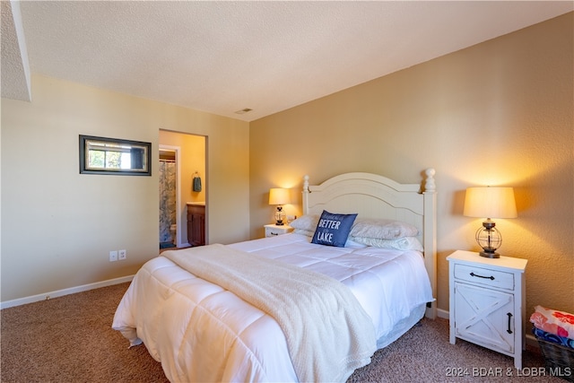 bedroom featuring carpet, ensuite bathroom, and a textured ceiling