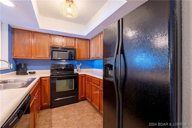 kitchen with a textured ceiling, black appliances, sink, and a raised ceiling