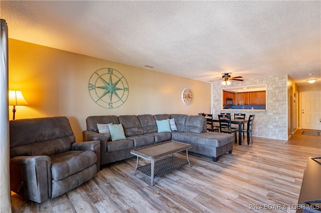 living room with wood-type flooring, a textured ceiling, and ceiling fan