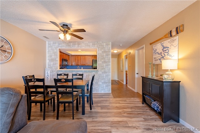 dining space featuring ceiling fan, light wood-type flooring, and a textured ceiling