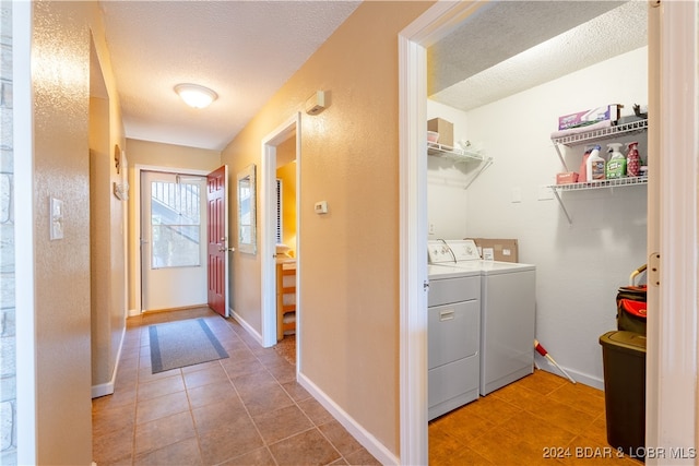 laundry area with washing machine and clothes dryer, tile patterned flooring, and a textured ceiling