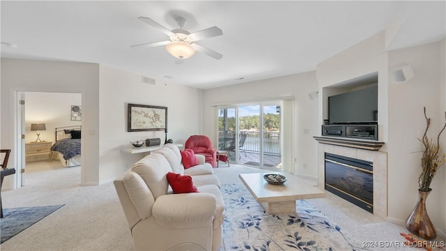 carpeted living room with a tile fireplace and ceiling fan