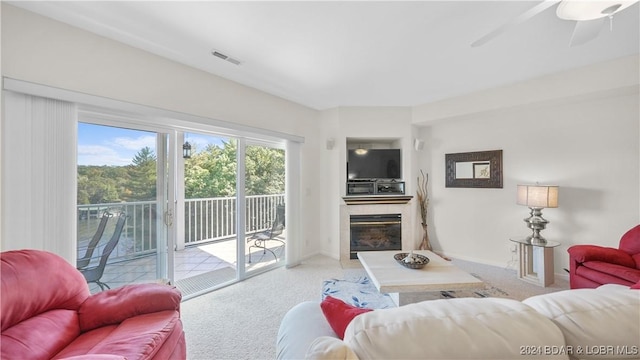 living room featuring a glass covered fireplace, visible vents, light carpet, and baseboards