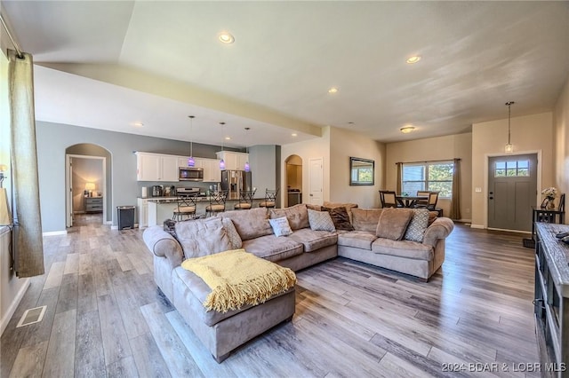 living room with light hardwood / wood-style floors and vaulted ceiling