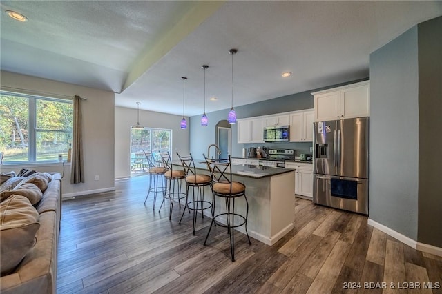 kitchen with a kitchen bar, white cabinetry, an island with sink, and appliances with stainless steel finishes