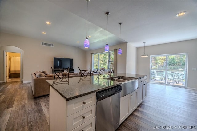 kitchen with a kitchen island with sink, white cabinets, hanging light fixtures, stainless steel dishwasher, and dark stone countertops