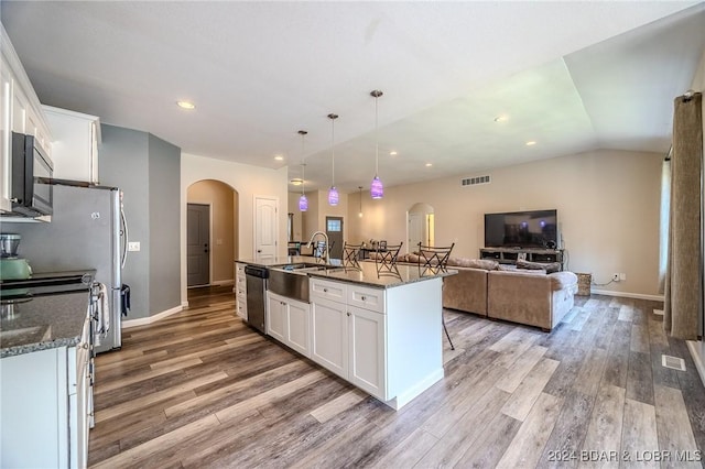 kitchen featuring white cabinets, pendant lighting, a center island with sink, and sink