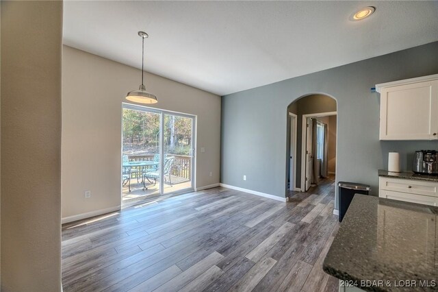 kitchen featuring white cabinets, dark stone counters, decorative light fixtures, and light wood-type flooring