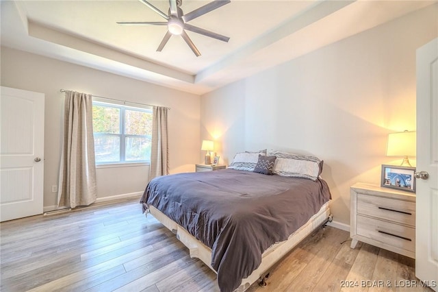 bedroom featuring a tray ceiling, light hardwood / wood-style flooring, and ceiling fan