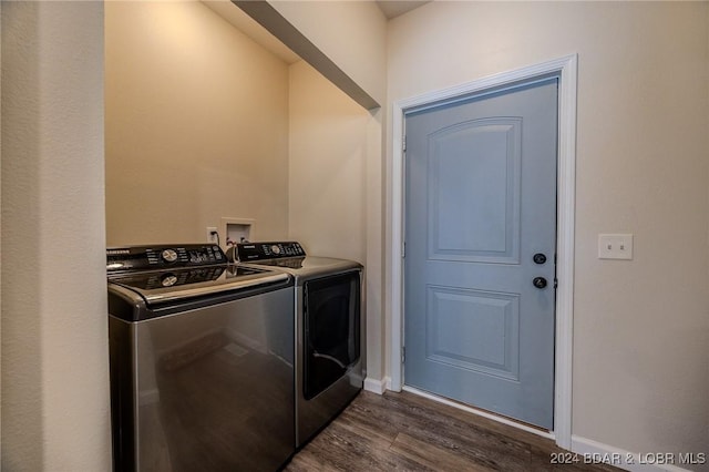 clothes washing area featuring washing machine and clothes dryer and dark wood-type flooring