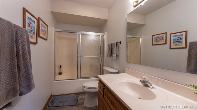 full bathroom featuring vanity, combined bath / shower with glass door, and toilet