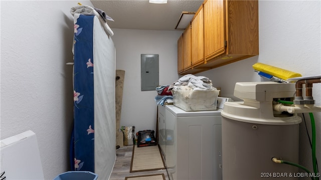 laundry area featuring cabinets, light hardwood / wood-style floors, a textured ceiling, washer and dryer, and electric panel