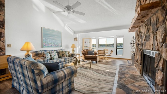 living area with a fireplace, ceiling fan, lofted ceiling, a textured ceiling, and wood finished floors