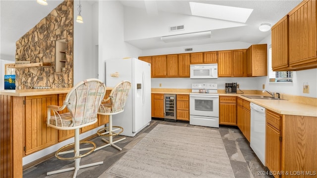 kitchen featuring vaulted ceiling with skylight, white appliances, beverage cooler, sink, and pendant lighting