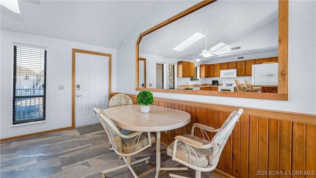 dining area featuring ceiling fan and lofted ceiling with skylight