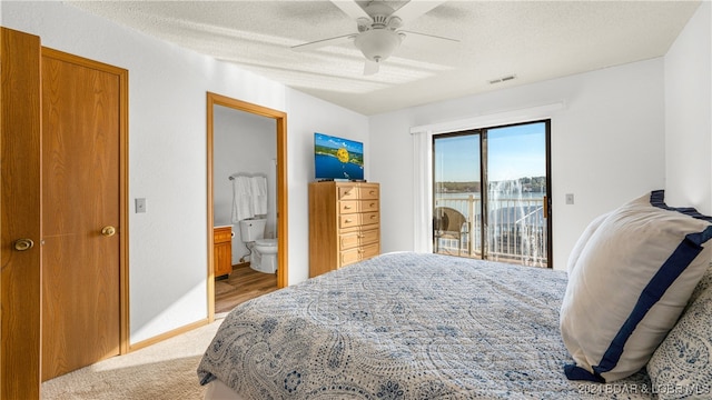 bedroom featuring access to outside, ensuite bathroom, ceiling fan, a textured ceiling, and light colored carpet