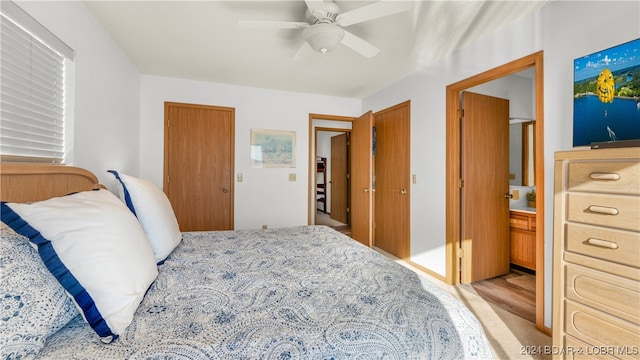 bedroom with ceiling fan, ensuite bathroom, and multiple closets