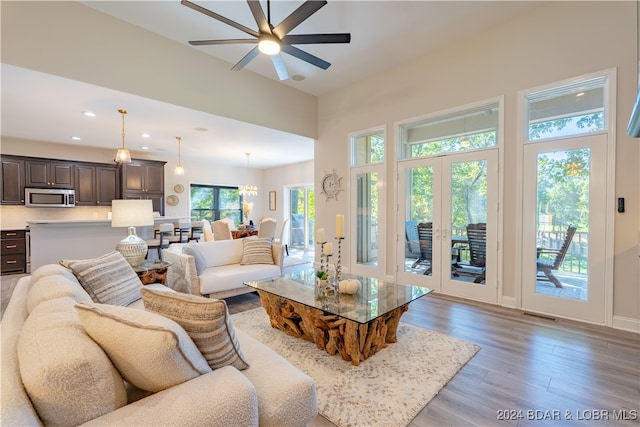 living room featuring ceiling fan with notable chandelier and light hardwood / wood-style floors