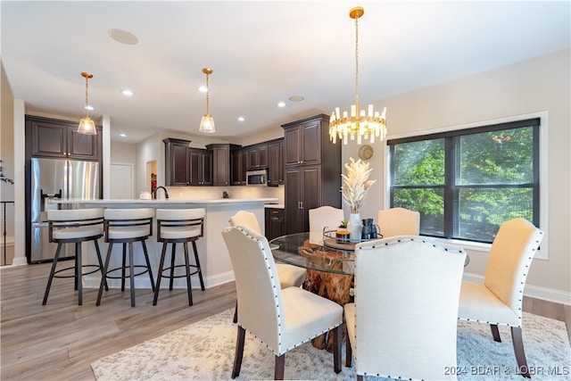 dining area with light hardwood / wood-style floors, an inviting chandelier, and sink