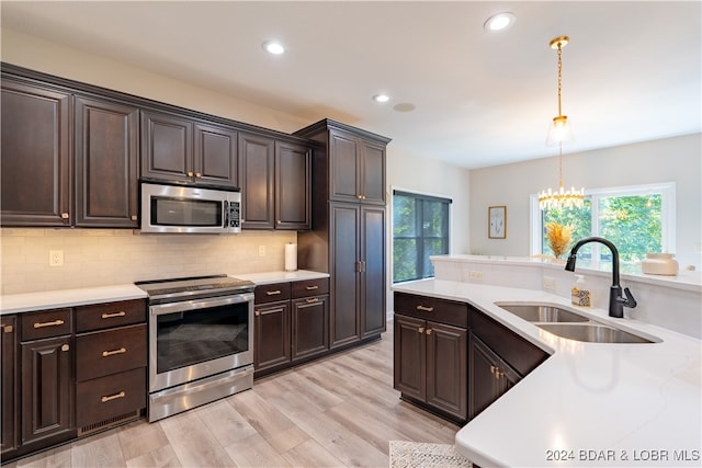 kitchen featuring sink, decorative light fixtures, light hardwood / wood-style flooring, appliances with stainless steel finishes, and decorative backsplash