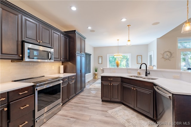 kitchen with stainless steel appliances, hanging light fixtures, sink, and plenty of natural light