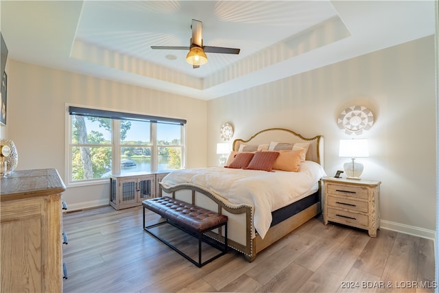 bedroom featuring a tray ceiling and light hardwood / wood-style flooring