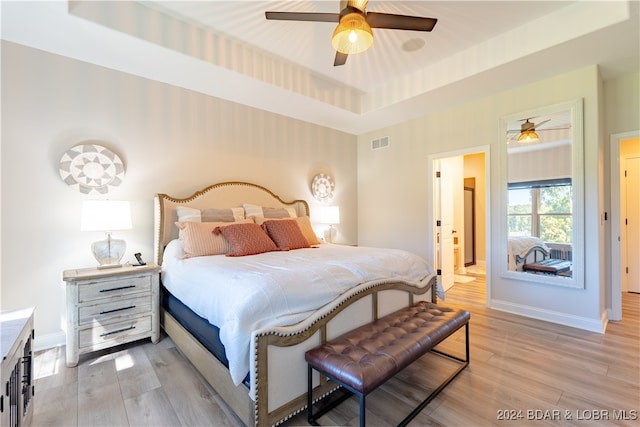 bedroom featuring a raised ceiling, light hardwood / wood-style flooring, and ceiling fan