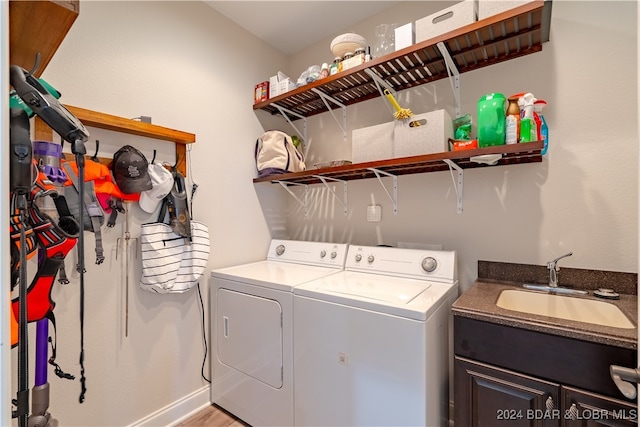 clothes washing area featuring light wood-type flooring, separate washer and dryer, sink, and cabinets