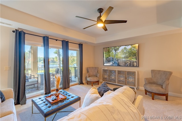 carpeted living room with ceiling fan, plenty of natural light, and a water view