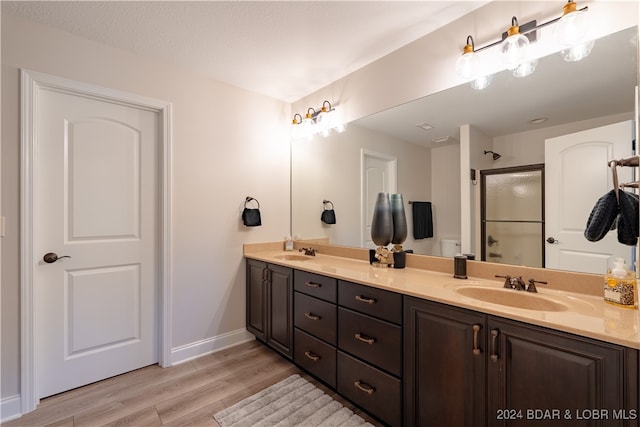 bathroom with hardwood / wood-style floors, a shower with door, and vanity